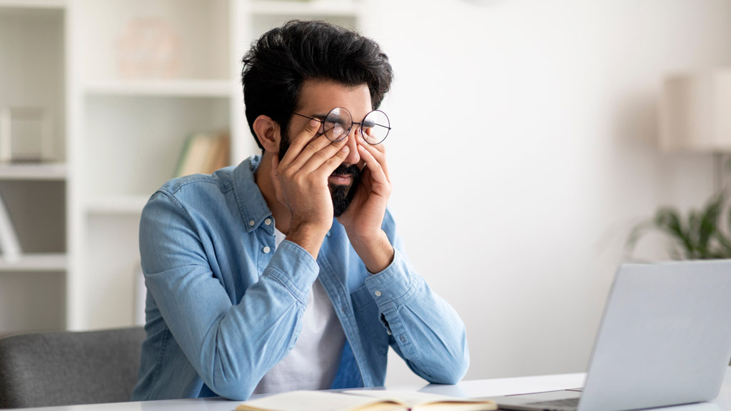 Mann stützt gestresst den Kopf in die Hände - Stress am Arbeitsplatz